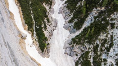 Aerial view of the mudflow with snow high in the Alpine mountains. clipart