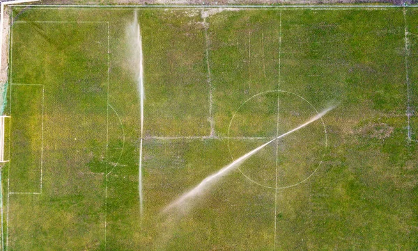 Aerial view of watering the lawn of a football field, top view.