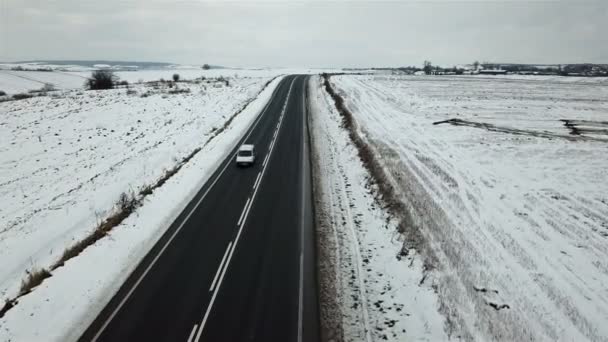 鳥瞰図で雪に覆われたフィールドの背景に冬の道 — ストック動画