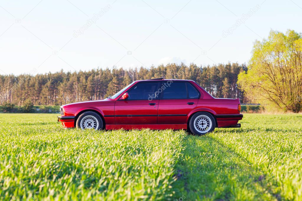 Front left side of an old German car that stands on green grass at sunset