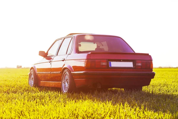 Das Heck des alten, roten deutschen Autos, das bei Sonnenuntergang auf dem Gras steht — Stockfoto