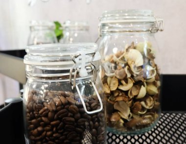 Mutfak malzemesi, kavrulmuş kahve çekirdekleri ve gümüş kapaklı cam kavanozlara kokulu çiçek.