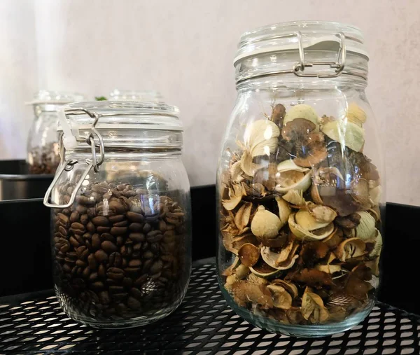 キッチン用品 コーヒー豆の焙煎 ガラス瓶銀キャップに香りのよい花 — ストック写真