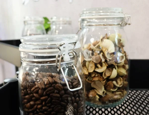 Mutfak malzemesi, kavrulmuş kahve çekirdekleri ve gümüş kapaklı cam kavanozlara kokulu çiçek.