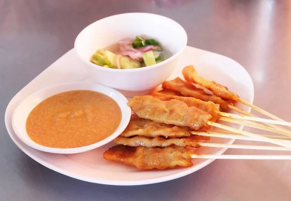 Satay de porco grelhado com salada de pepino em um prato — Fotografia de Stock