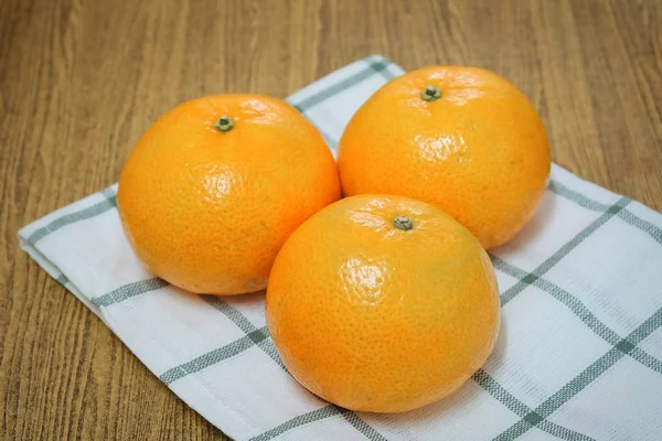 Três laranjas maduras em uma mesa de madeira — Fotografia de Stock