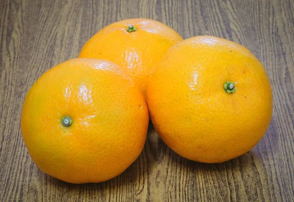 Trzy dojrzałe pomarańcze na drewnianym stole — Zdjęcie stockowe