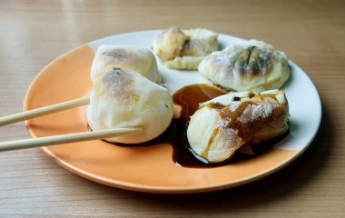 Bir çift çubuk sıcak, ızgara bir yakimochi 'yi lezzetli bir soya sosuna batırır ve lezzetli ve popüler bir geleneksel Japon aperatifi yaratır..