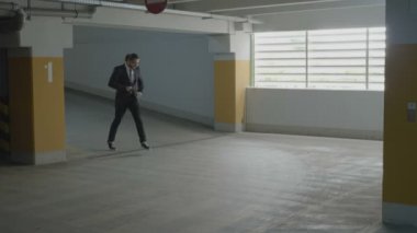 Teşvik ediliyor onun mutluluğunu ifade etmek için genç güzel işadamı dans ve sevinçle bir yer altı park yerinde atlama komik