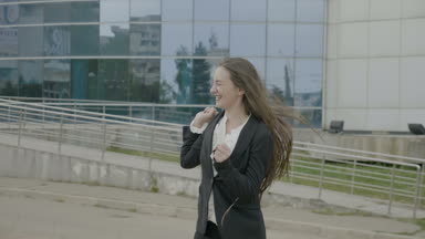 Sevinçle Doğa şirket önünde dans office kıyafeti giymiş mutlu güzel genç iş kadını