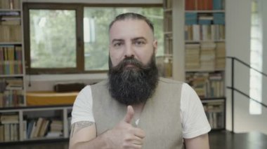 Bir başparmak yukarıya tepki sahip sakallı genç çekici adam