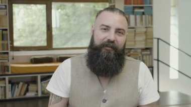 Kameraya bakarak ve bir iş görüntülü arama toplantıda konuşan sakallı serin bir genç adam, reaksiyon