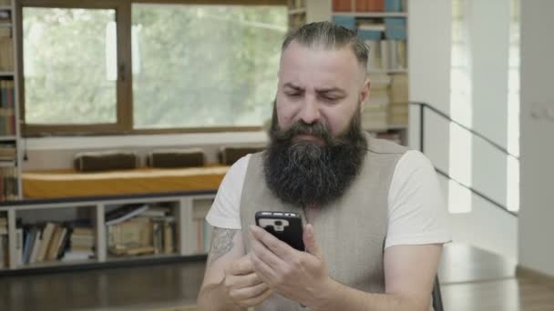 Homem de negócios sonolento com reação de barba quando ele tenta ler bocejo e se concentrar em sua tela de smartphone no escritório — Vídeo de Stock