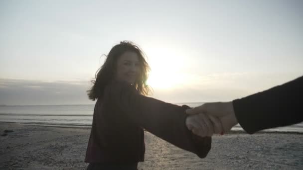 Молода пара тримає руки дівчина, провідний хлопець, що йде до моря схід сонця на порожньому пляжі POV концепція подорожі в повільному русі — стокове відео