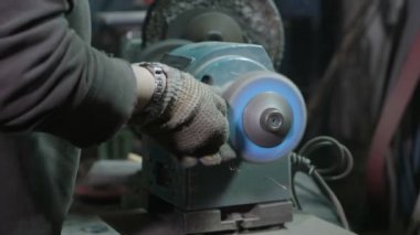 Onun atölyesinde bir taşlama makinesi kullanarak metal parlatma kadın demirci
