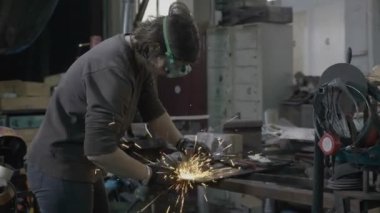Profesyonel kadın kaynakçı veya koruma araçları giyen demirci yumuşak çelik ve demir onun atölyesinde taşlama kıvılcım