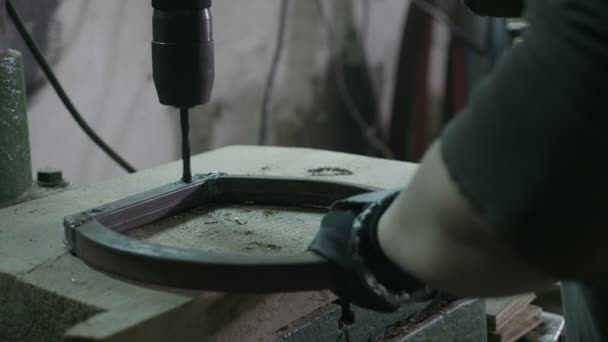 Arbeiterin mit einer Bohrmaschine, um Löcher in ein Metallstück in ihrer Werkstatt zu bohren