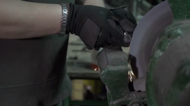 Hands of woman blacksmith polishing a metal screw head using a grinding machine that makes sparkles in a workshop in slow motion — Stock Video