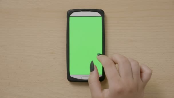 Молода жінка з сенсорним екраном смартфон змінює медіаконтент з пальцем на зеленому дисплеї — стокове відео
