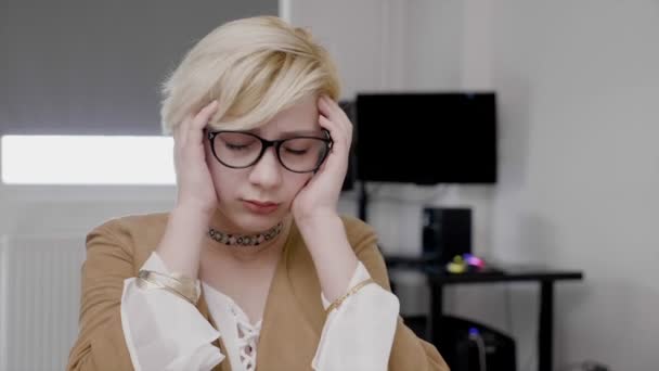 Молодая блондинка-бизнесвумен, страдающая мигренью, терла голову изнуренной и напряженной в офисе — стоковое видео