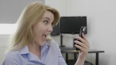 Sürpriz neşeli kadın girişimci onun iş sonuçları cep telefonunda duygu memnun ve heyecan başarı ve başarı kavramı ile ilgili iyi haber alma