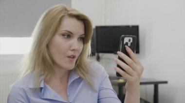 Rahatsız edici bir şey izlerken ekran şok bakarak smartphone kullanarak sosyal medya ağı üzerinde sörf kadın çene bırakılan ofis