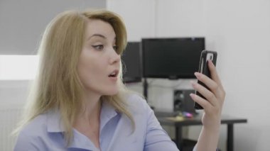 Muhteşem gülümseyen iş kadını webcam selam ofisinde Smartphone kullanarak görüntülü arama yapma