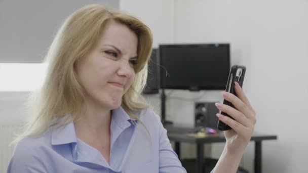 Empleada joven descontenta con desgaste formal en el trabajo contenido de medios deslizantes en la pantalla de su teléfono inteligente agitando la cabeza no en total desacuerdo — Vídeos de Stock