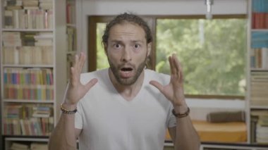 İyi görünümlü genç adam çene ve yükseltilmiş eller sürpriz ve şok evde bırakarak ile reaksiyon