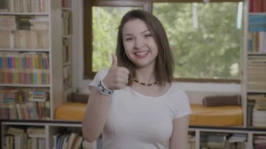 Gülümseyen ve başparmak gösterilmesini neşeli genç kadın portresi