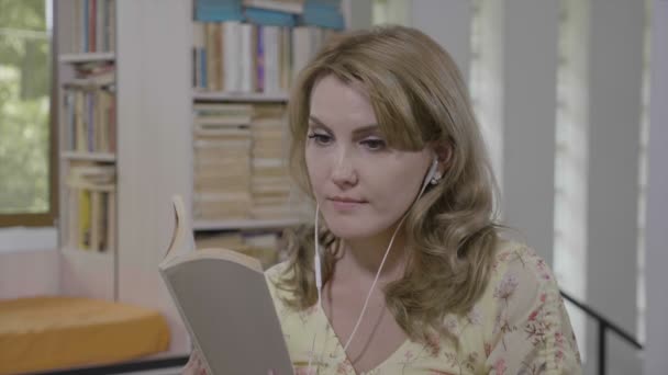 在图书馆听音乐的迷人的学生妇女放松阅读书 — 图库视频影像