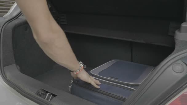 若い男が休暇の準備ができての車のトランクの中の彼の旅行バッグの準備 — ストック動画