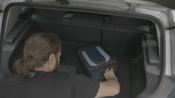 若いの男車と休暇のため荷物の再編成からアンロードのトラベル バッグ — ストック動画