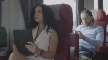 Bin yıllık ofis teknoloji bağımlılığı tablet ve smartphone onların yolculuk sırasında kullanarak tren üzerinde erkek ve kadın commuters giyinmiş