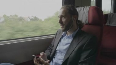 Mutlu gülen kurumsal adam eğleniyor trenle üzerinde çalışmaya commuting kulaklıklar üzerinde favori müzik dinleme