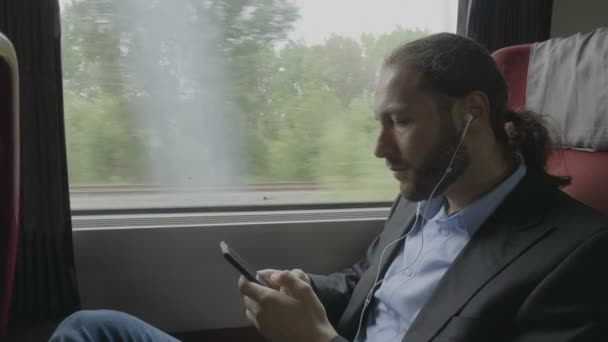 千禧企业家航海家在火车上放松的肖像 在智能手机和耳机上听音乐 — 图库视频影像