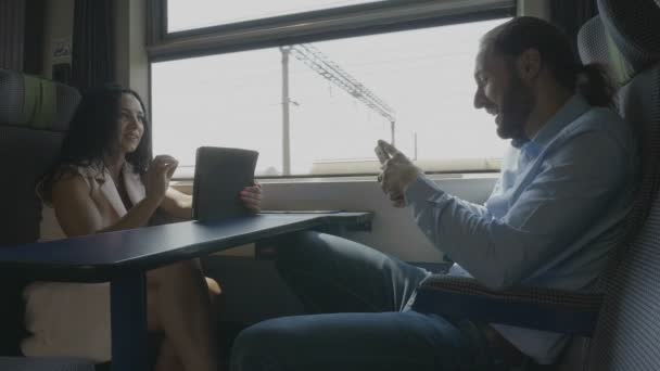 年轻的旅游夫妇在假期旅行的火车有乐趣交谈和使用他们的数字智能设备在旅途中 — 图库视频影像