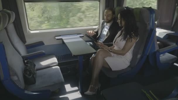若い企業のカップル男女のビジネスについて議論するプロジェクトのデバイスのタブレット と電車で旅しながらスマート フォンを使用して — ストック動画