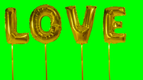 Word love from helium golden balloon letters floating on green screen — Stock Video