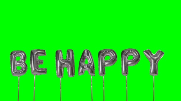 Word be happy from helium silver balloon letters floating on green screen — Stock Video
