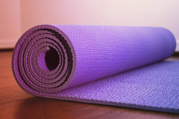 Purple yoga mat with soft pastel effect on gym floor