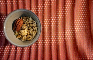 Bambu arka planda ceviz ve kopya alanı ile granola kase üst görünümü 