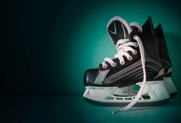 Hockey skates over white bench with green radial gradient background with copy space