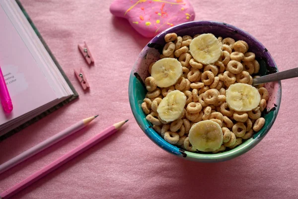 Pembe arka plan üzerinde kitap ve kalem ile Tahıl Cheerios Bowl 
