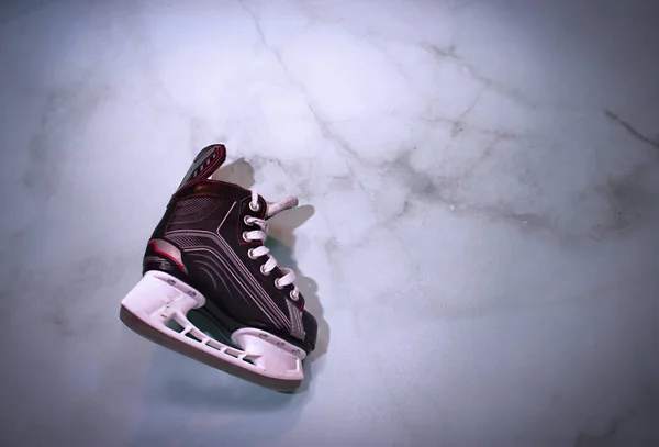 Hockey skate hanging over marble gradient background with copy space