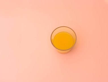 Kopya alanı ile şeftali pembe arka plan üzerinde izole portakal suyu bir bardak üst görünümü 