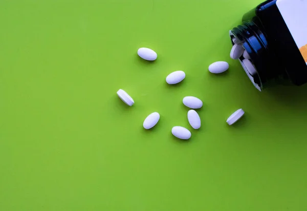 Top view of bottle of medicines on bright green background with copy space