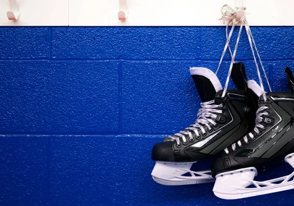 Hockey skates hanging over blue wall with copy space