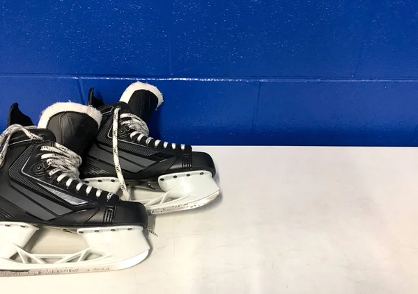 Hockey skates over white bench in locker room with copy space