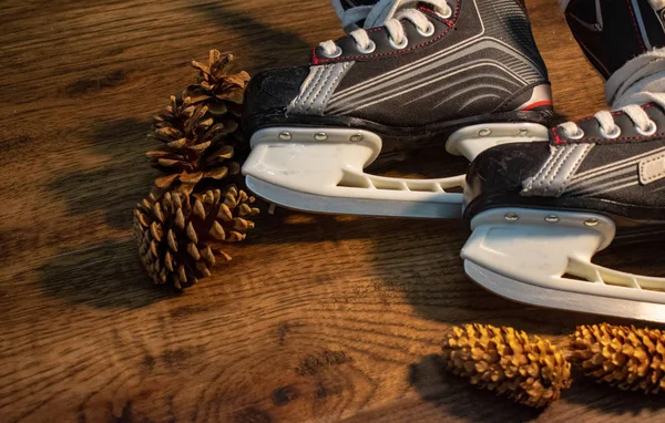 Hockey skates in wooden Christmas background with pinecones